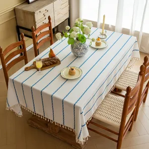 Detail van minimalistisch rechthoekig tafelkleed met blauwe strepen en beige kwastjes