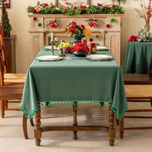 Detail van donkergroen tafelkleed met franje afwerking op een feestelijke houten tafel