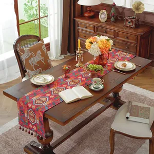 Dettaglio del runner da tavola rosso etnico con motivi jacquard e nappe fatte a mano