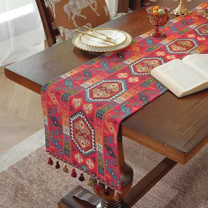 Dettaglio del runner da tavolo jacquard rosso con motivi boho e nappe fatte a mano