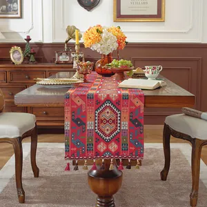 Dettaglio del runner da tavola bohémien in tessuto rosso con motivi jacquard e nappe