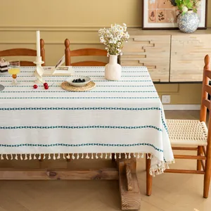 Detail van gebroken wit polyester tafelkleed met blauwe golfstrepen en witte kwastjes