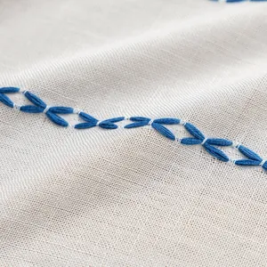 Close-up of geometric blue embroidery on cream polyester stripe curtain fabric