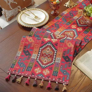 Dettaglio runner da tavola boho rosso con motivi geometrici e nappe fatte a mano