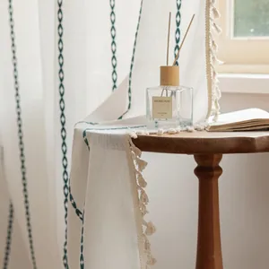 Detailed view of blue embroidered chain patterns and beige tassels on striped curtains
