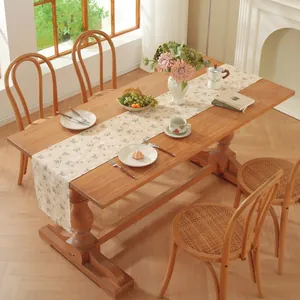 Détail d'un chemin de table style crème française avec feuilles vertes et motifs floraux