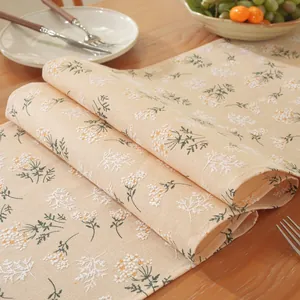 Détail d'un chemin de table floral avec fond crème et petites fleurs blanches
