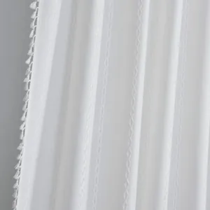 Detail of white striped curtain fabric with tassel fringe and geometric jacquard texture