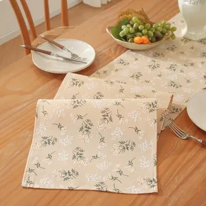 Gros plan du chemin de table crème avec broderie florale sur une table en bois
