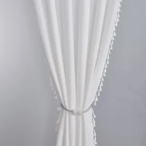 Close-up of white striped curtain with wavy embroidery, tassels and pearl tieback