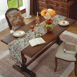 Dettaglio del runner da tavolo vintage in cotone e lino con eleganti nappe su tavolo scuro