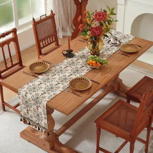 Dettaglio del runner da tavola jacquard floreale con frange su un tavolo di legno rustico