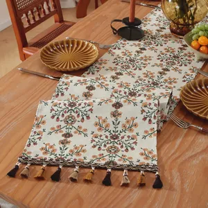 Dettaglio runner da tavola boho con ricamo floreale e nappe colorate pendenti