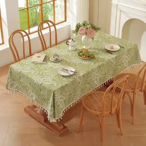 Détail de nappe verte à motif de feuilles blanches et bords à franges pour salle à manger