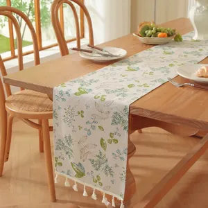 Détail de chemin de table à motif floral avec pompons blancs sur une table en bois