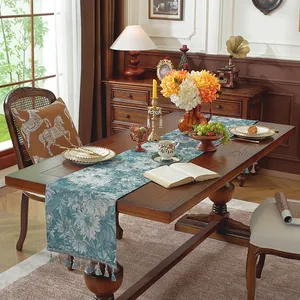 Dettaglio del runner da tavola jacquard blu con nappe decorative su tavolo in legno