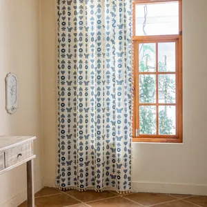 Detailed view of beige curtains with blue patterns and handmade tassels in a cozy room