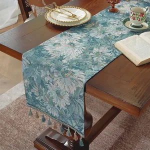 Dettaglio di runner da tavola jacquard floreale con eleganti nappe su tavolo in legno