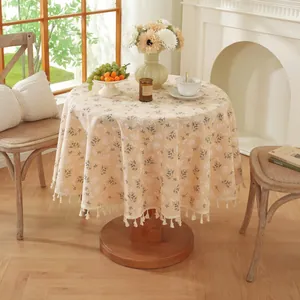 Nappe ronde fleurie avec franges beiges sur table en bois dans une salle à manger