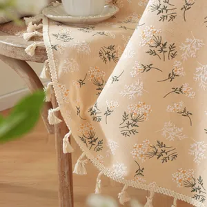 Détail d'une nappe ronde florale avec glands sur une chaise en bois vintage