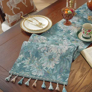 Dettaglio di runner da tavola jacquard floreale con nappe su tavolo in legno
