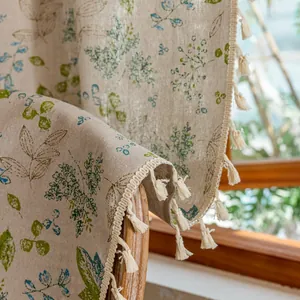 Detail of beige cotton linen curtain fabric with leaf print and cream tassel edges