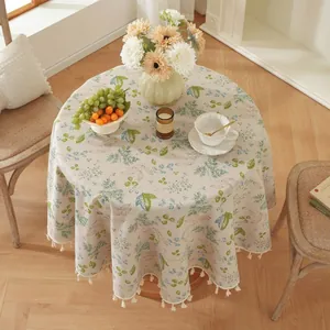 Détail de la nappe ronde à motifs floraux avec feuilles et bordure à franges blanches