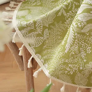 Détail de la nappe en lin vert avec motif floral blanc et finitions à franges