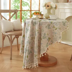 Nappe ronde à fleurs avec pompons, texture lin et motif feuilles sur table en bois