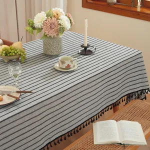 Détail d'une nappe en coton et lin à rayures grises avec des glands noirs décoratifs