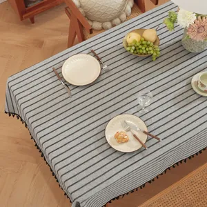 Détail de la nappe à rayures grises avec pompons noirs et décoration de table chic