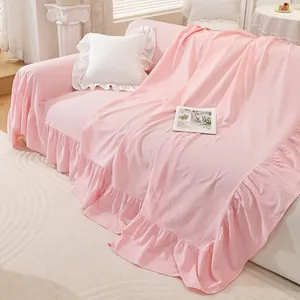 Detail of light pink cotton sofa cover featuring elegant ruffled edges and soft texture
