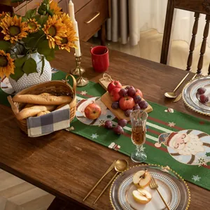 Dettaglio del runner da tavola natalizio verde con motivo Babbo Natale e nappe decorative