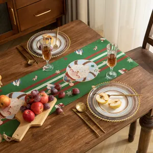 Runner da tavola natalizio verde con motivi di Babbo Natale e frange sul tavolo di legno