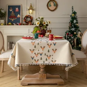 Beige Christmas tablecloth with reindeer print, green trees and white pom pom tassels