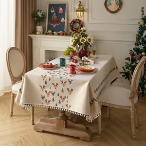 Close-up of festive Christmas tablecloth with elk patterns and white pom-pom trim detail