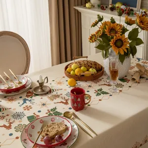 Detail of Christmas tablecloth featuring festive reindeer and tree patterns on beige fabric