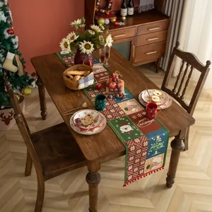 Dettaglio di un runner da tavola natalizio con nappe e motivi festivi lavorati a maglia