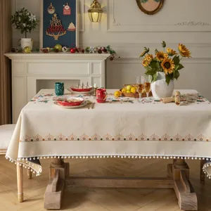 Beige Christmas tablecloth with reindeer and snowflake patterns and white pom-pom fringe