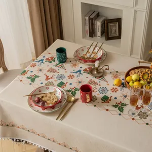 Detail of Christmas tablecloth with beige snowflakes, reindeer patterns and pompom fringe