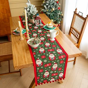 Dettaglio del runner da tavola natalizio verde con motivi di Babbo Natale e pompon rossi