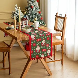 Dettaglio del runner da tavola natalizio verde bosco con jacquard e nappe a pompon rossi