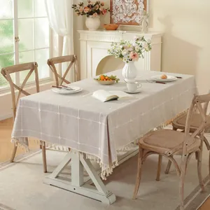 Detalle de mantel de cuadros con borlas de flecos en una mesa de comedor de madera