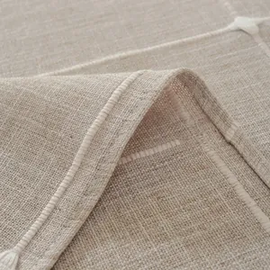 Detalle macro de mantel beige efecto lino con bordado blanco y detalles de borlas