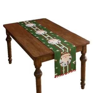 Runner da tavola natalizio verde con motivi Babbo Natale e pompon rossi su tavolo di legno