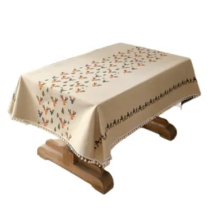 Beige kersttafelkleed met rendierpatroon en witte pomponfranjes voor een feestelijke tafel