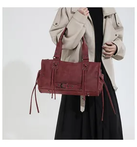 Detail of burgundy leather tote bag with long tassels and vintage metal eyelets