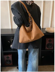Bruine suède hobo-tas met vintage houten kralenhanger gedragen door een model