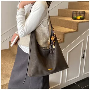 Detailopname van de suède hobo tas met decoratieve houten kralen en lederen kwastjes