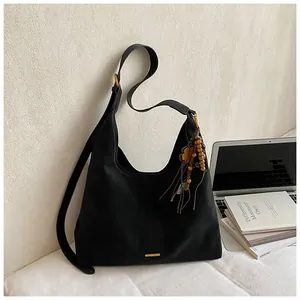 Detailopname van zwarte suède hobo tas met etnische kwastjes en houten kralen versiering